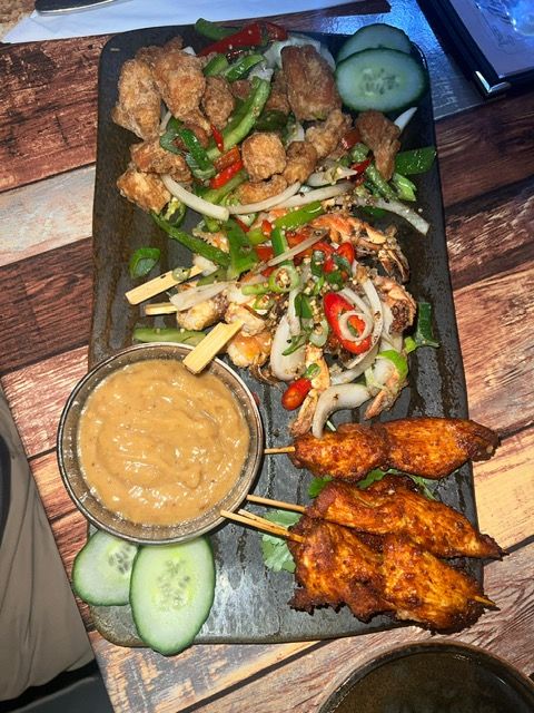 Chinese sharing board with salt and pepper chicken, aromatic strips and satay skewers with peanut sauce